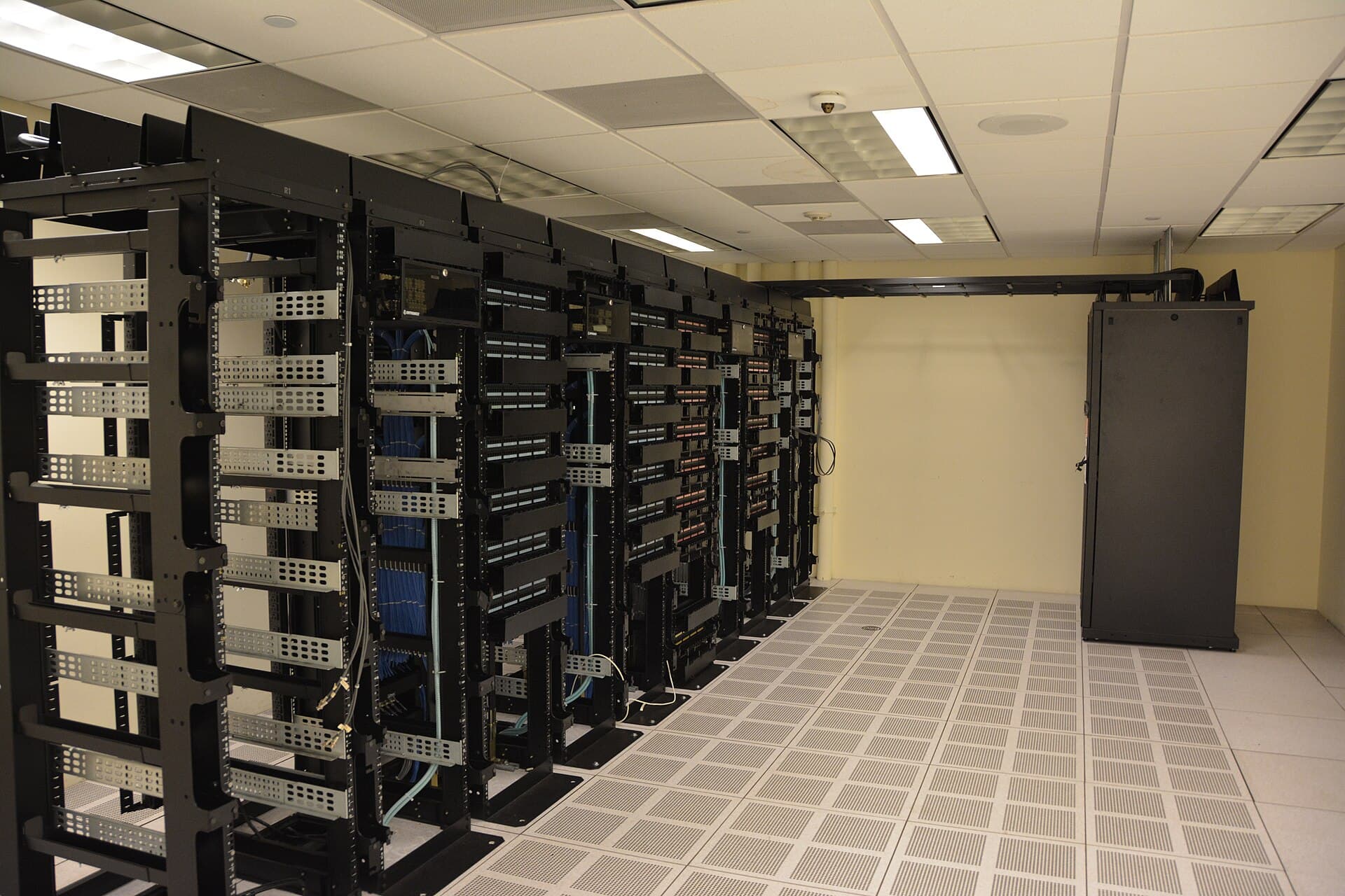 Rows of black server racks with network cabling in a data centre room
